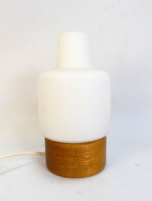 a white table lamp with a wooden base and a white glass shade