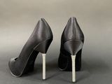 pair of black high heeled shoes with crystal heels on a gray background