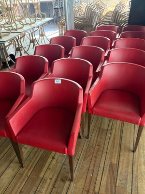 several red chairs are lined up in a row on a wooden floor