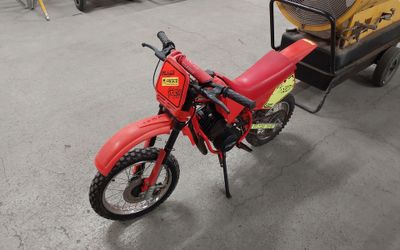 a red dirt bike parked in a garage with a trailer behind it