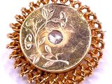 an image of a gold colored broochle with a stone in the center