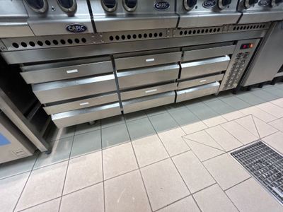 Plusieurs fours en acier inoxydable sont alignés sur le sol d'une cuisine