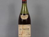 une bouteille de vin « La Tache » posée sur une table, sur fond gris