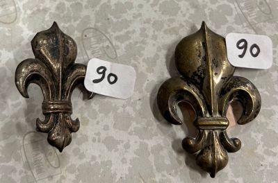 deux fleurs de lys en métal posées sur une table, accompagnées d'une étiquette de prix
