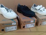 Trois paires de baskets blanches et noires sont posées sur un carton.