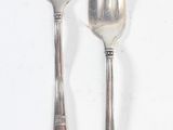 two forks and a spoon sitting on a white surface