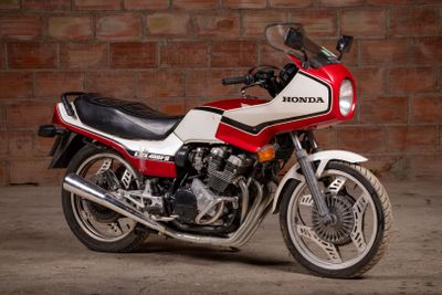 a red and white motorcycle parked in front of a brick wall
