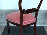 a wooden chair with a pink seat on a black mat