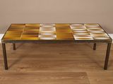 une table basse avec un plateau en carrelage posée sur un parquet