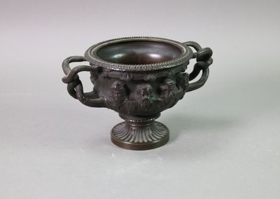 un vase en bronze orné d'une tête de lion