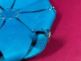 an origami flower made out of blue paper on a red surface