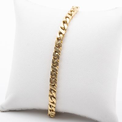 a gold bracelet on a pillow on a white pillow
