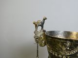 a silver vase with a chain hanging from it ' s handle