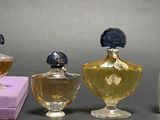 three bottles of perfume sitting next to each other on top of a purple box