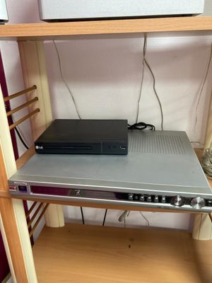un lecteur DVD posé sur une étagère, à côté d'une lampe