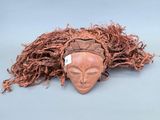 une image représentant un masque en bois aux longs cheveux sur fond bleu