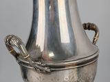 a silver vase with a dragon handle on a pedestal