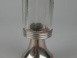 a small glass jar with a metal base on a white surface
