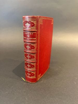 an old red book sitting on top of a table next to a gray wall