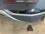 the rear end of a silver car with a license plate on it