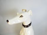 une statue de chien blanc avec un collier noir autour du cou