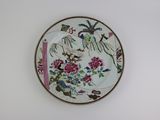 une assiette décorée de fleurs et d'oiseaux, accrochée au mur