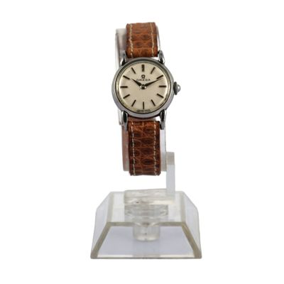 une photo d'une montre avec un bracelet en cuir marron posée sur un socle transparent