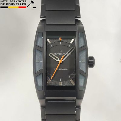 une montre noire avec un cadran noir et des aiguilles orange