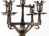 a tall metal candelier with five candles on it