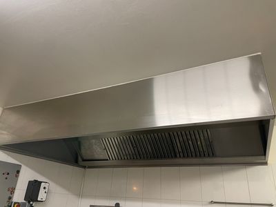 une hotte en acier inoxydable installée au-dessus d'une cuisinière dans une cuisine