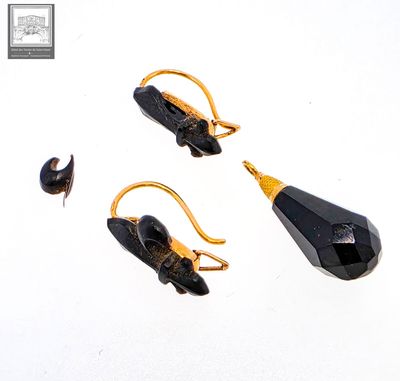 paire de boucles d'oreilles noires et dorées ornées d'une pierre noire facettée