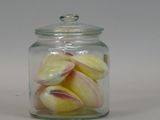 a glass jar filled with peeled fruit on a white surface