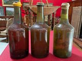 three empty bottles sitting on a table with a red table cloth