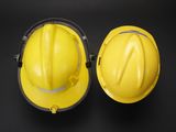 two yellow hard hats sitting next to each other on a black surface