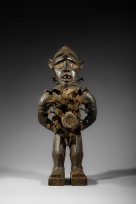 une statue en bois représentant un homme tenant une fleur