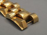 gros plan d'un bracelet en or sur une surface grise