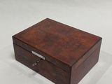a small wooden box with a metal handle on a white surface