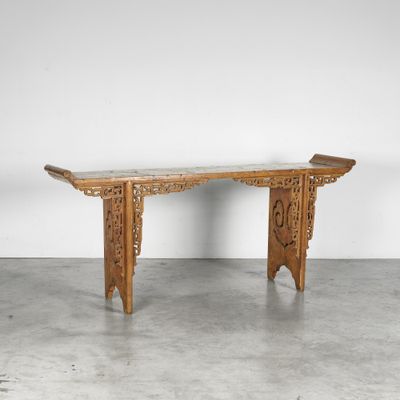 une table en bois avec un plateau en marbre posée sur un sol en béton
