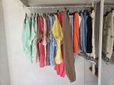many shirts hanging on a rack in a room