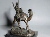 bronze statue of a man riding a camel with a spear in his hand