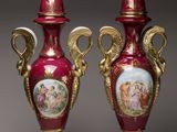 pair of red vases with gold handles and pictures on them