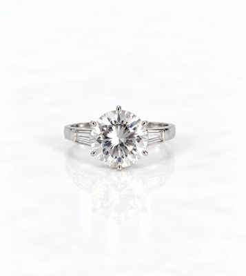 une bague de fiançailles en or blanc sertie d'un diamant rond taille brillant entouré de diamants taille baguette