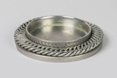 une assiette en argent entourée d'une corde torsadée sur un fond blanc