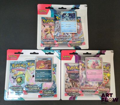 Trois paquets de cartes Pokémon se trouvent dans un paquet posé sur une table