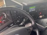 a steering wheel and dashboard of a truck with a tv in the background