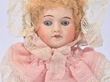 a doll that is wearing a pink dress and a hat