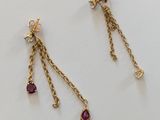 une paire de boucles d'oreilles en or et rubis posées sur un fond blanc