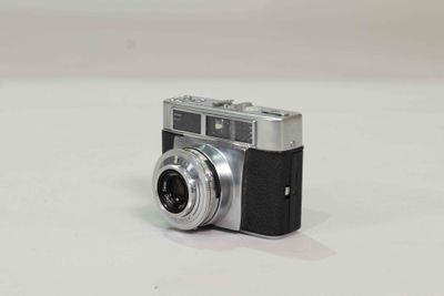 a small silver camera sitting on a white surface