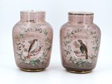 two vases with birds painted on them sitting on a table