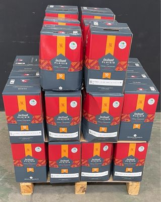 Plusieurs caisses de bière sont empilées sur une palette devant un mur noir.